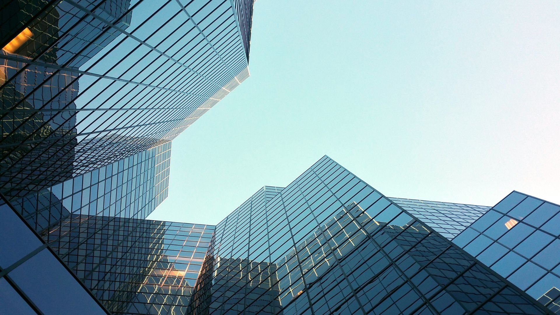 Modern glass skyscrapers reflecting sky, viewed from low angle perspective