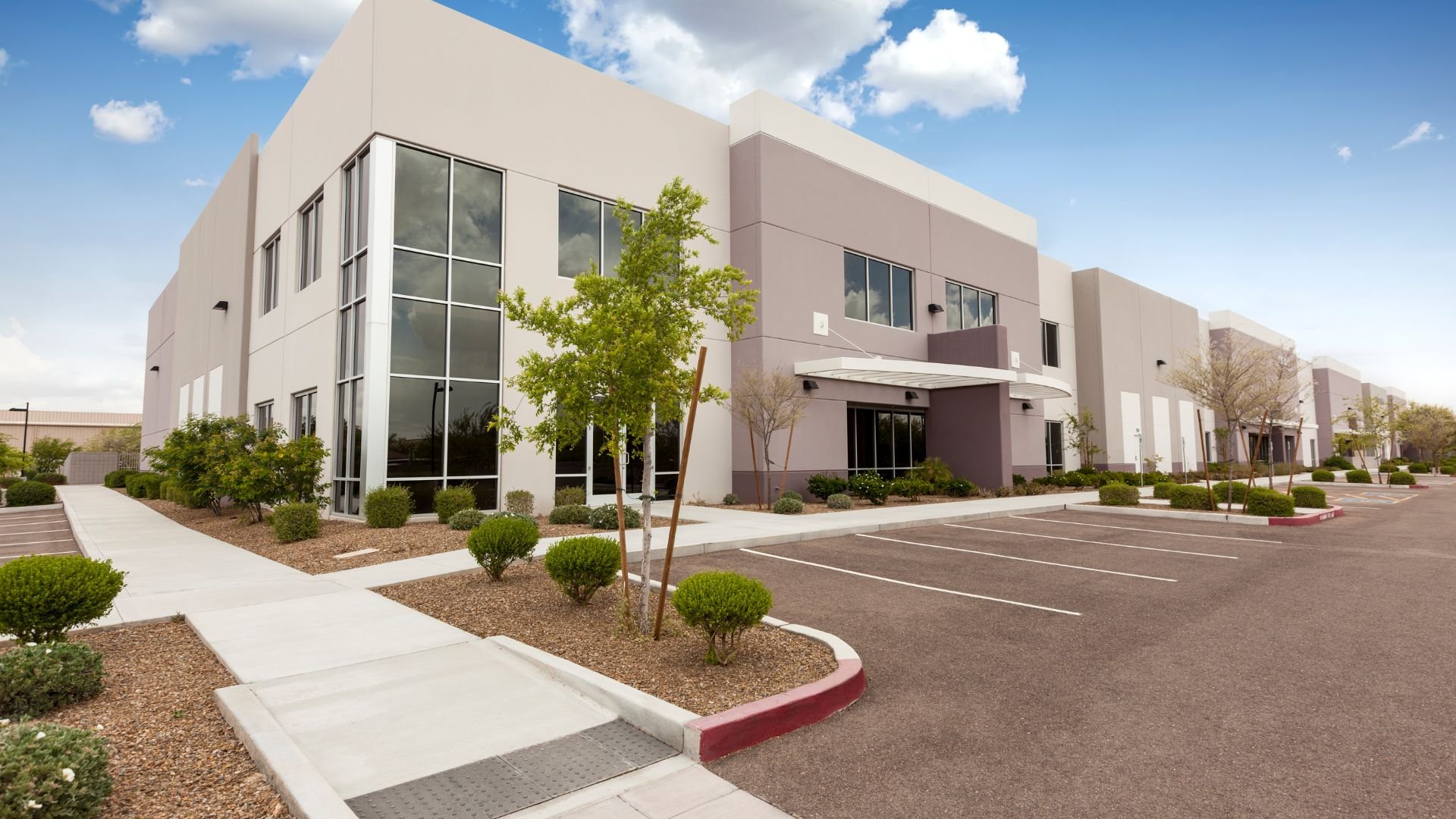 Modern office building with landscaped parking lot on sunny day
