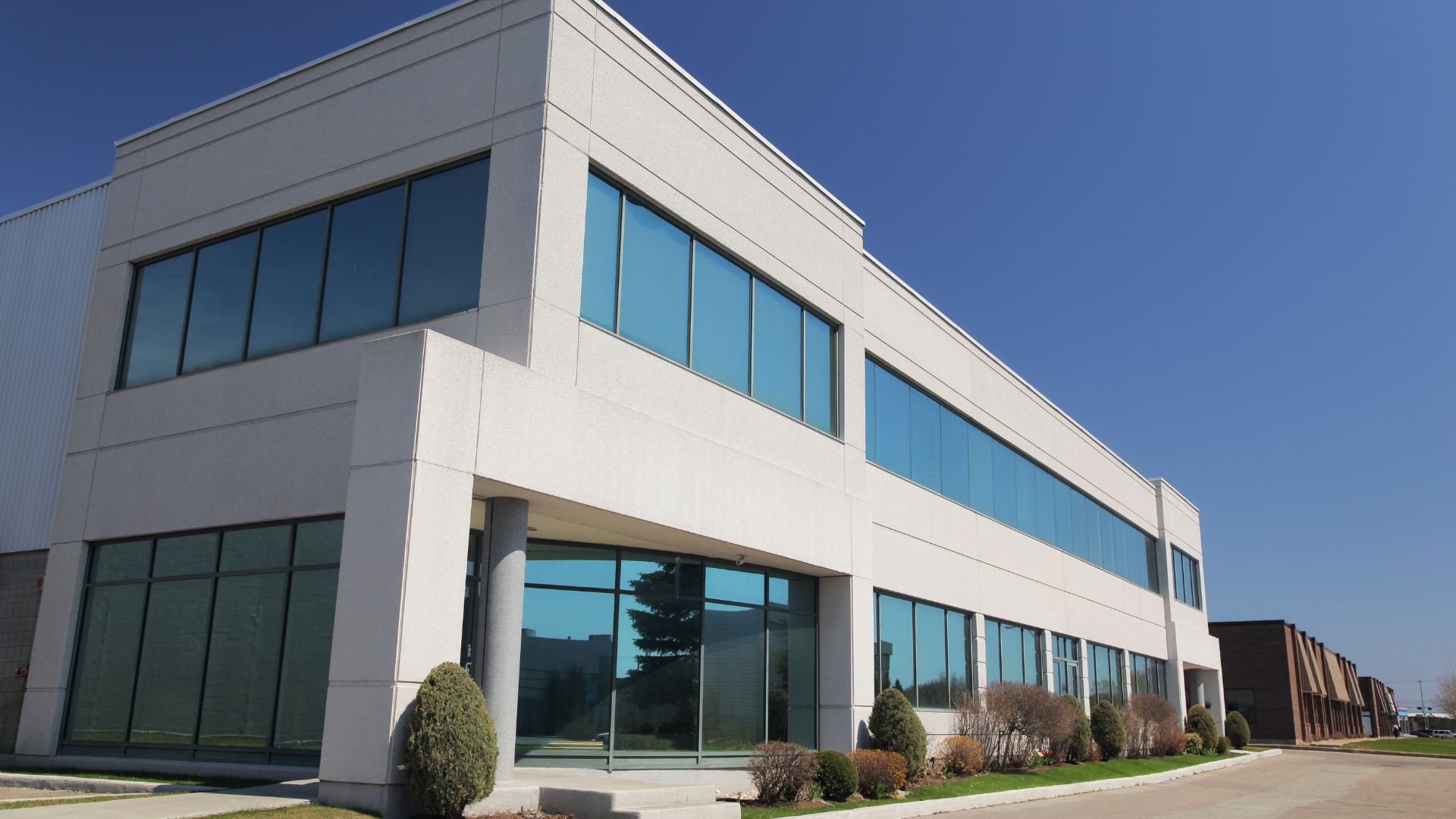Modern white office building with large blue windows on sunny day