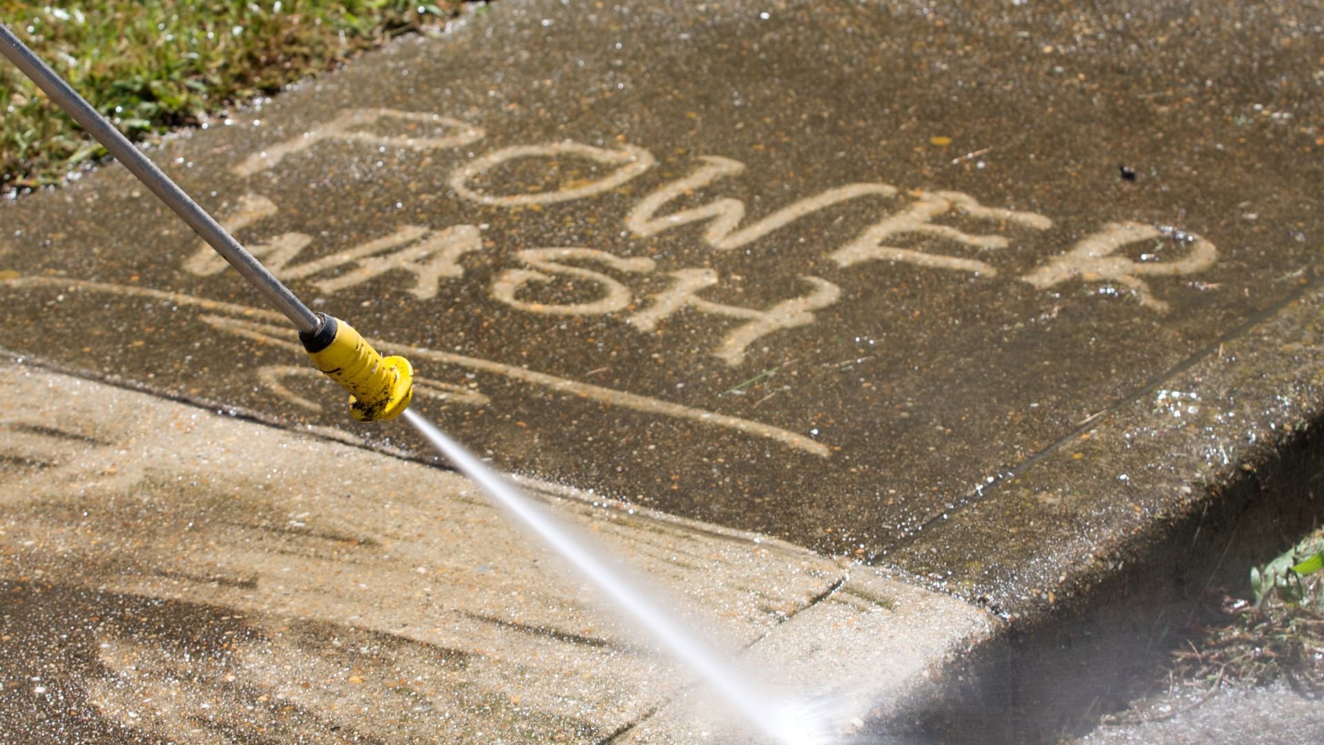 Power washer cleaning concrete surface with high-pressure water stream